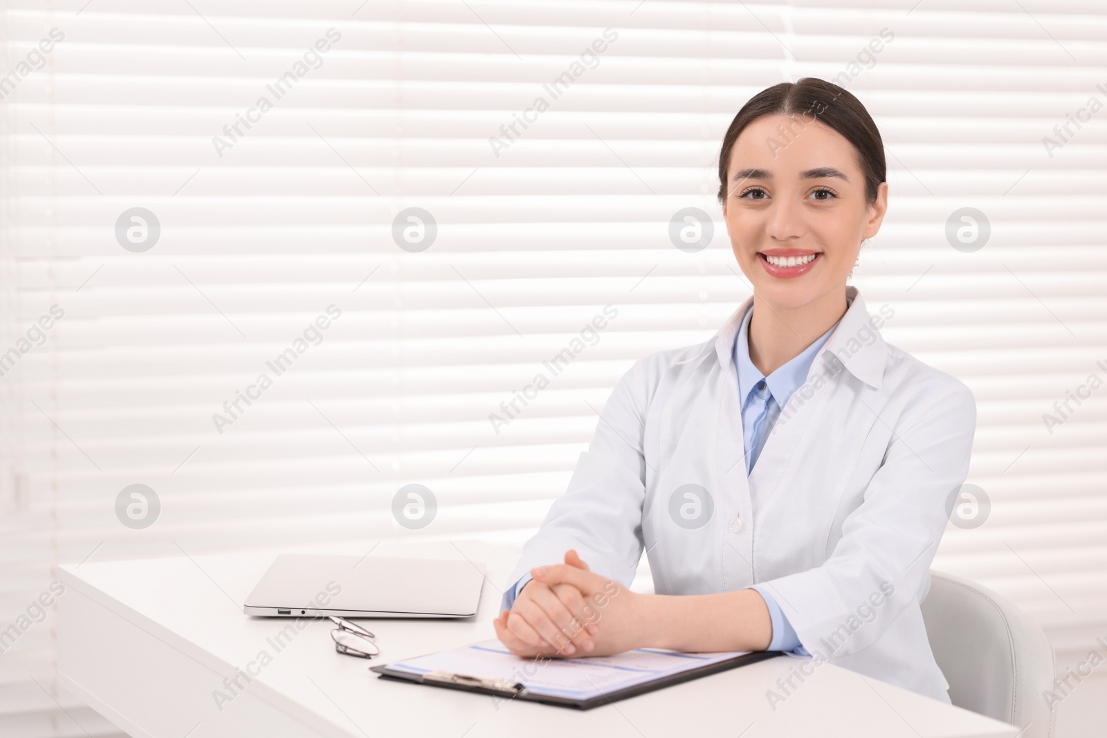 Photo of Medical consultant at table in clinic, space for text