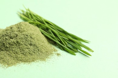 Pile of wheat grass powder and fresh sprouts on green table, closeup. Space for text