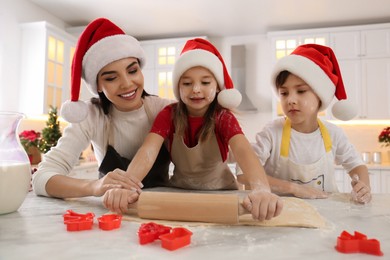 Photo of Mother and her cute little children making Christmas cookies in kitchen