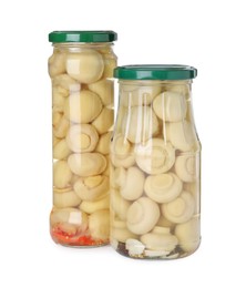 Jars with marinated mushrooms on white background