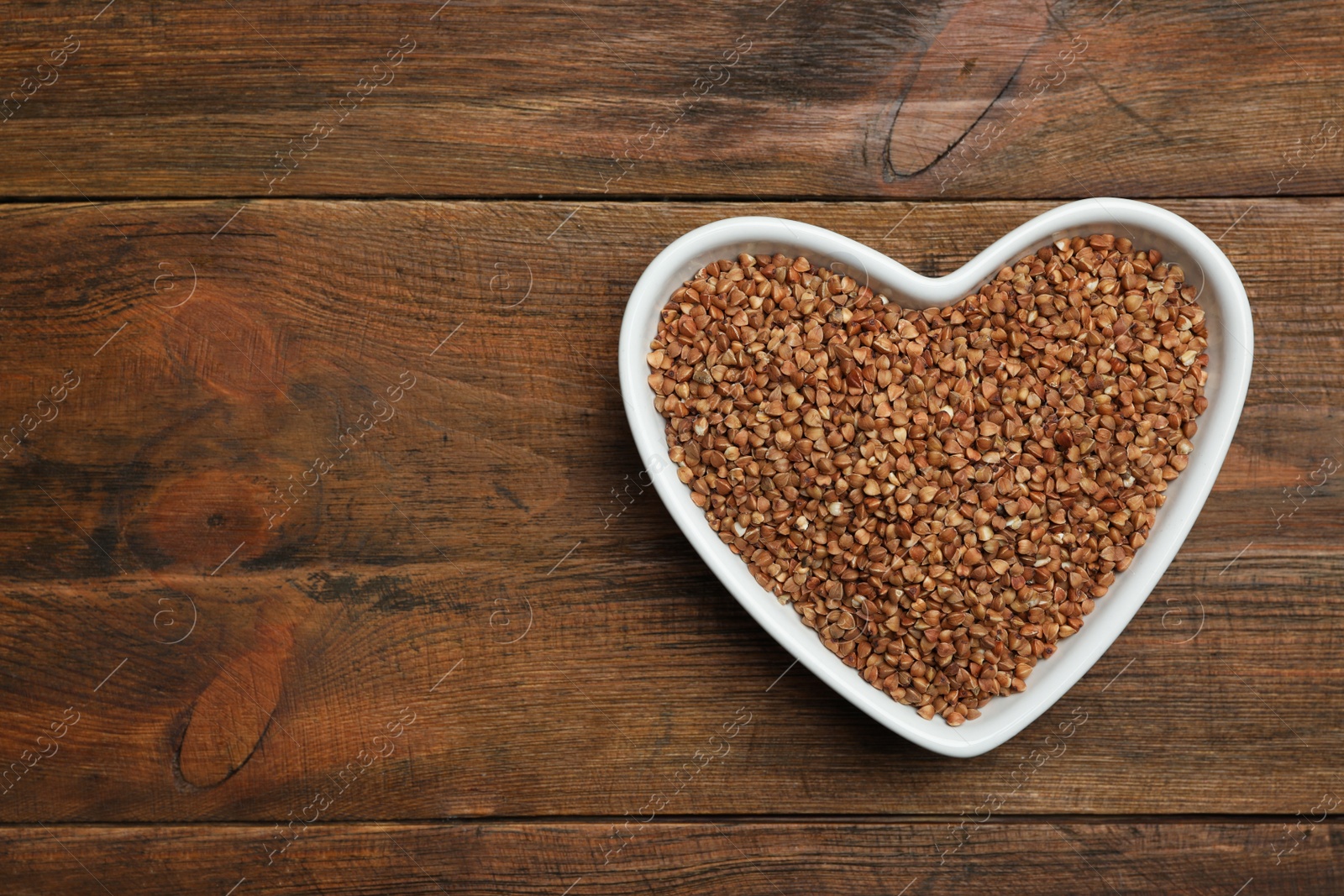 Photo of Buckwheat grains on wooden table, top view. Space for text