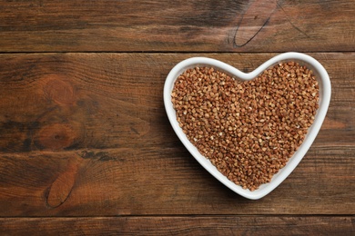 Photo of Buckwheat grains on wooden table, top view. Space for text