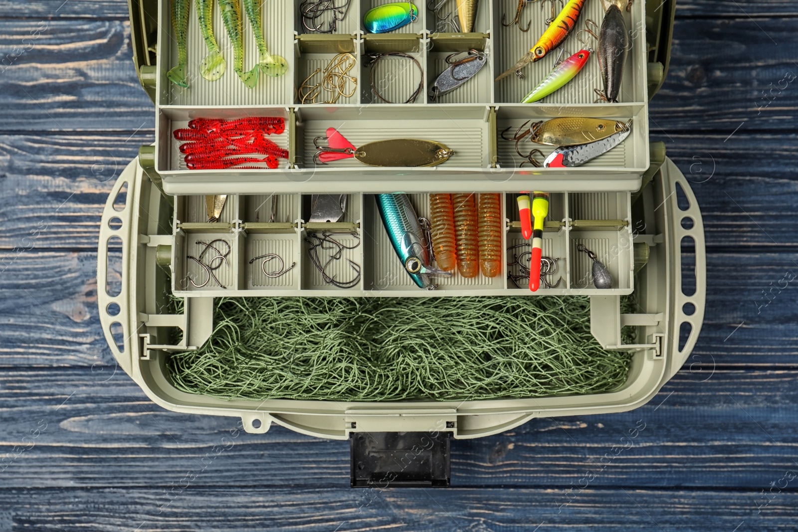 Photo of Box with different fishing accessories on wooden background, top view