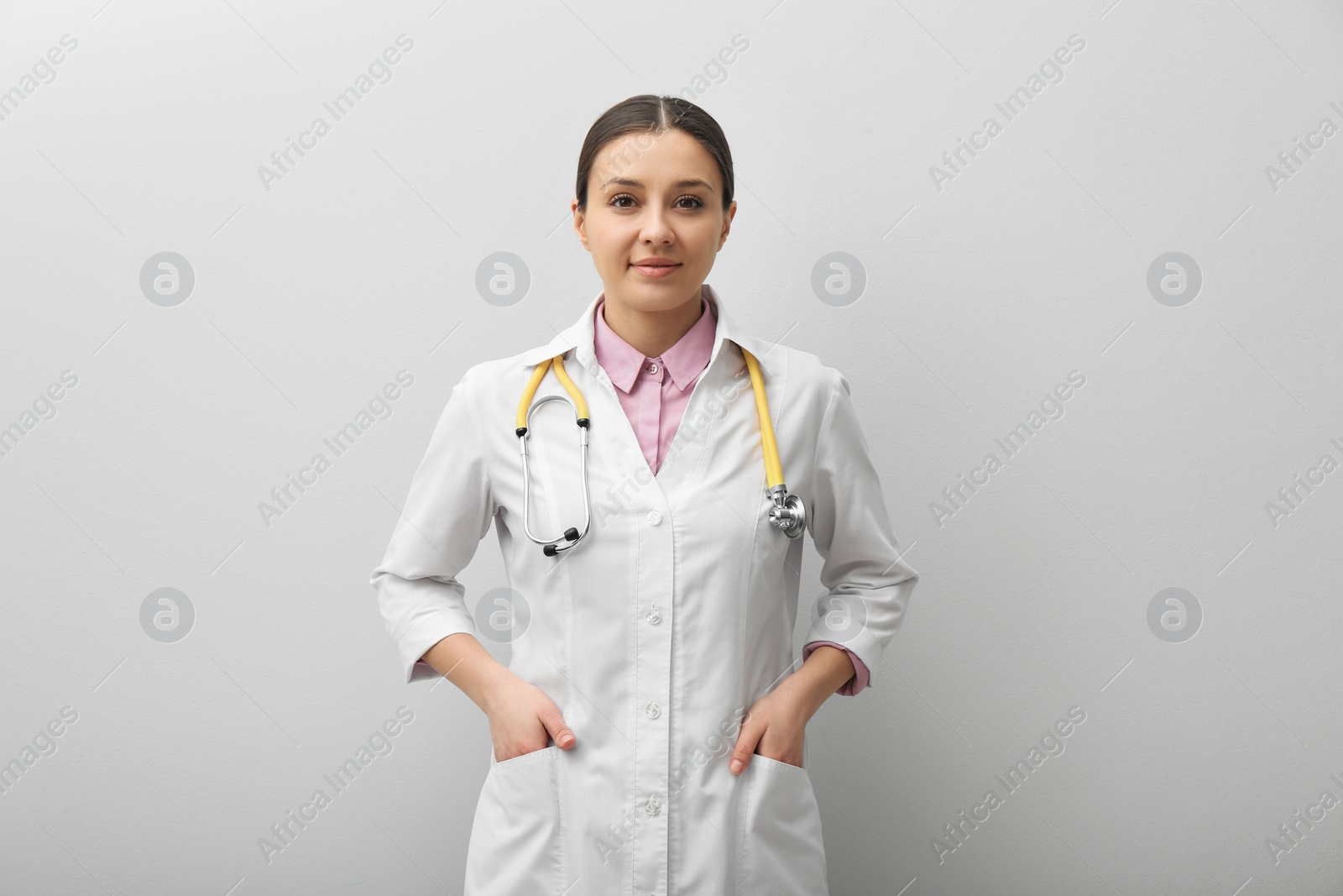 Photo of Pediatrician in uniform with stethoscope on light grey background