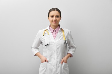 Pediatrician in uniform with stethoscope on light grey background