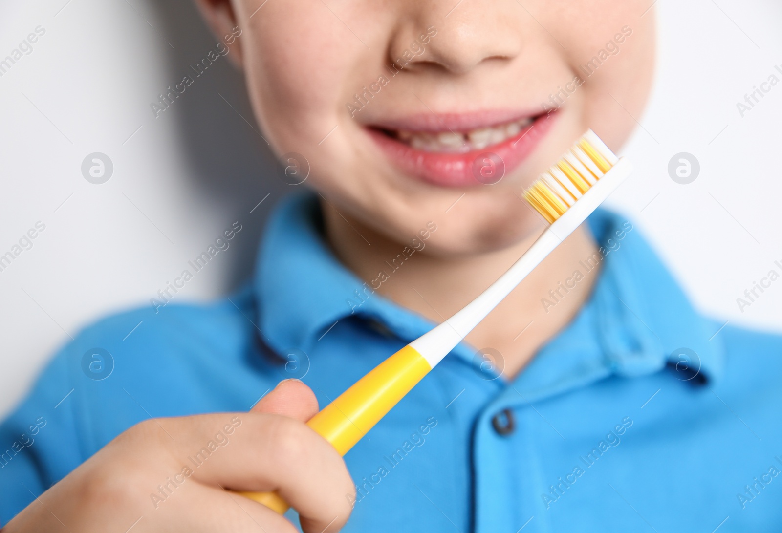 Photo of Little boy with toothbrush on light background, closeup