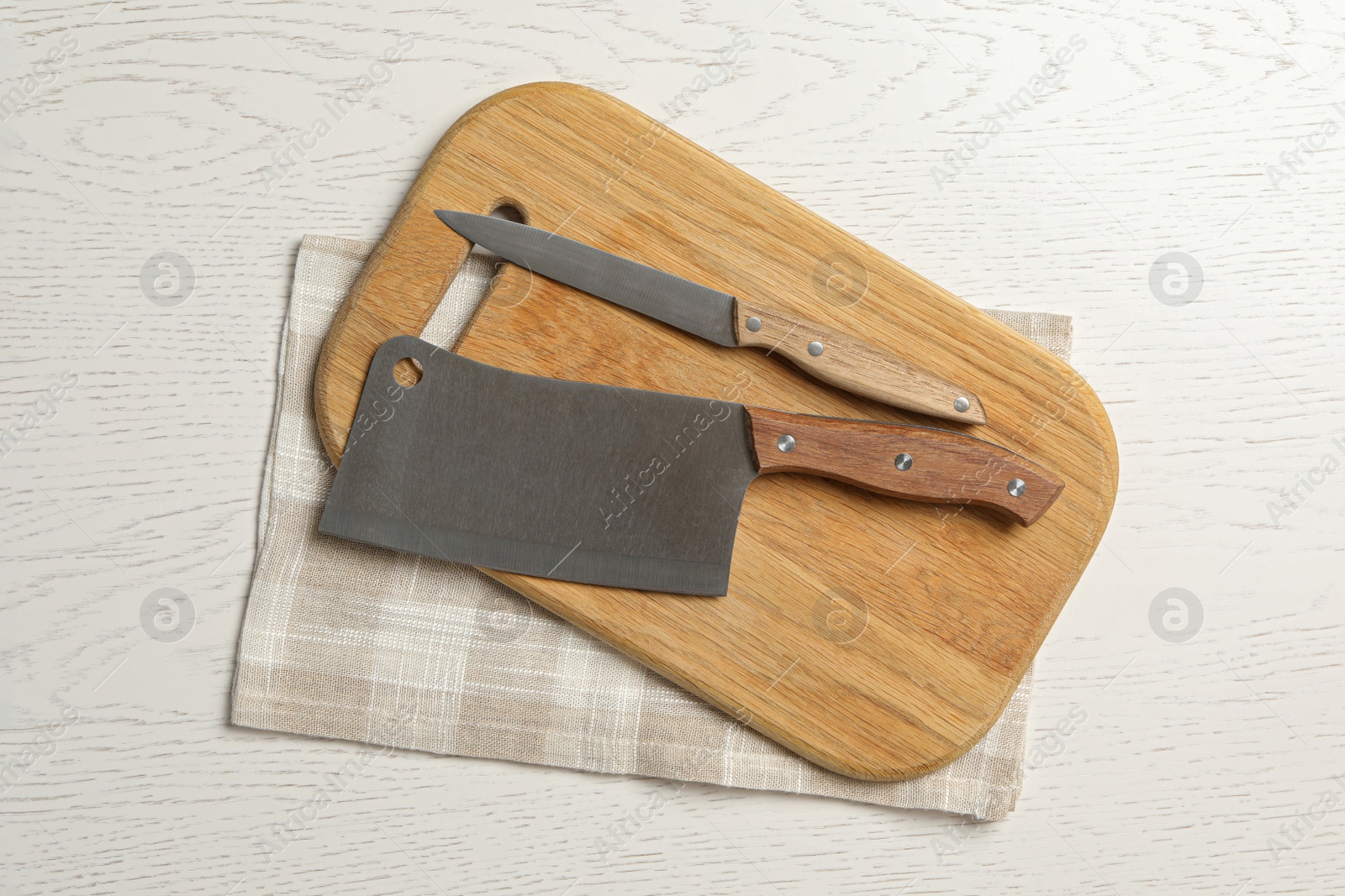 Photo of Knives, cutting board and towel on white wooden background, flat lay. Cooking utensils