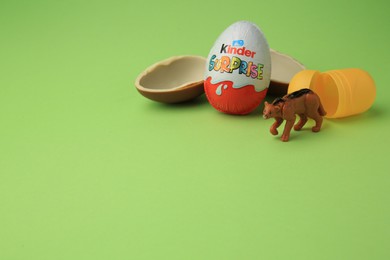 Sveti Vlas, Bulgaria - June 29, 2023: Kinder Surprise Eggs, plastic capsule and toy puma on light green background, space for text
