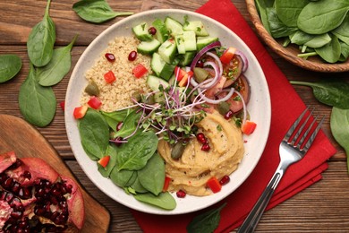 Delicious vegan bowl with cucumbers, spinach and bulgur on wooden table, flat lay