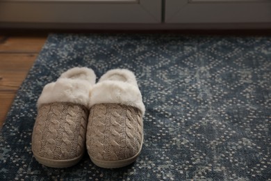Pair of beautiful soft slippers on rug in room. Space for text