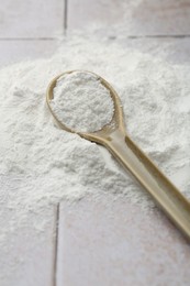 Photo of Pile of baking powder and spoon on light tiled table, closeup