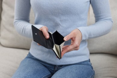 Photo of Woman with empty wallet on sofa indoors, closeup