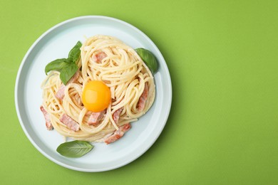 Photo of Delicious pasta Carbonara with egg yolk on light green background, top view. Space for text