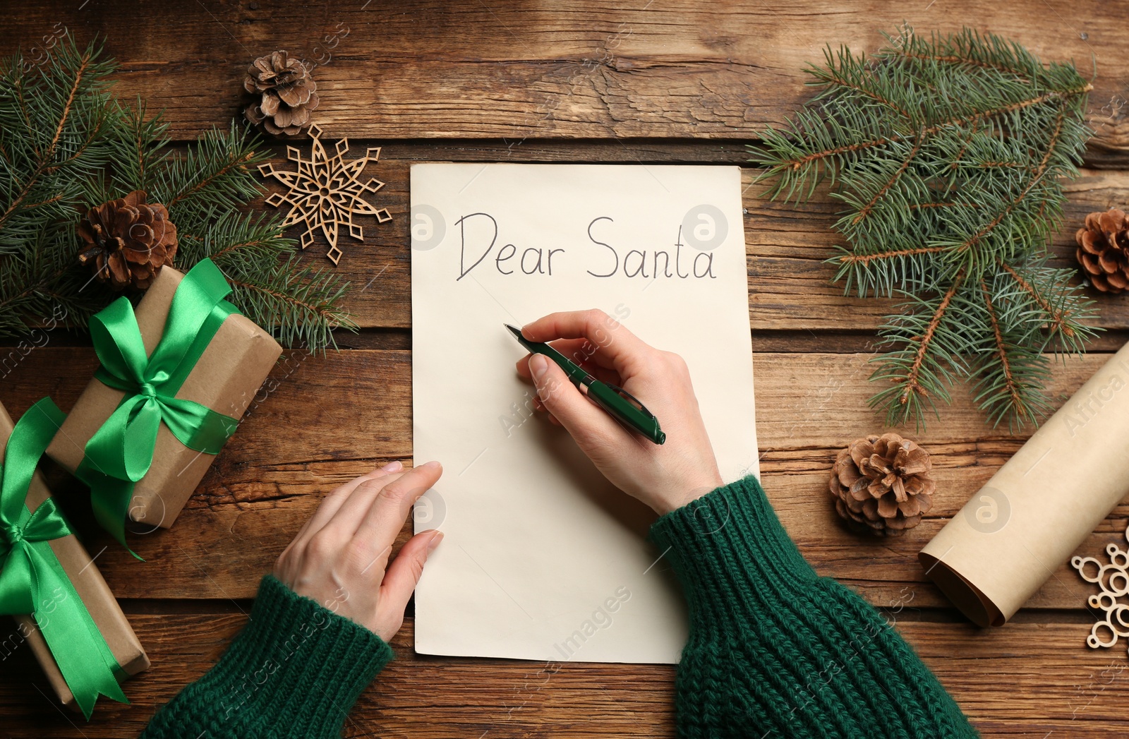 Photo of Top view of woman writing letter to Santa at wooden table, closeup