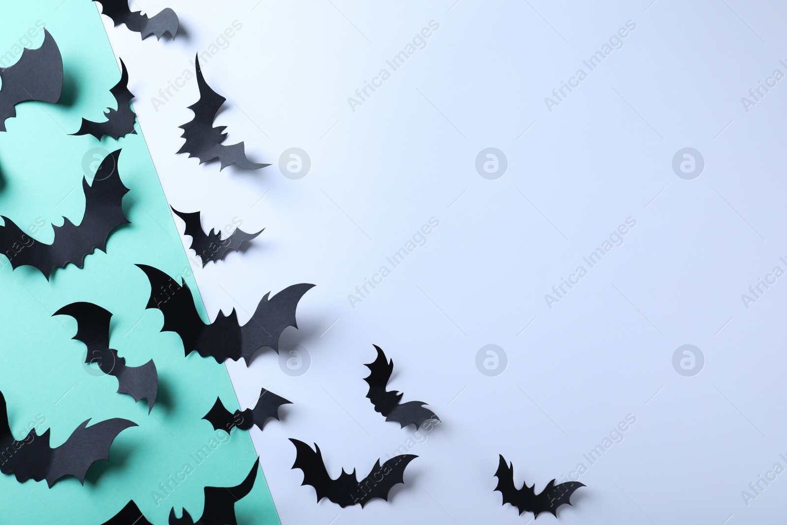 Photo of Many black paper bats on color background, flat lay with space for text. Halloween decor