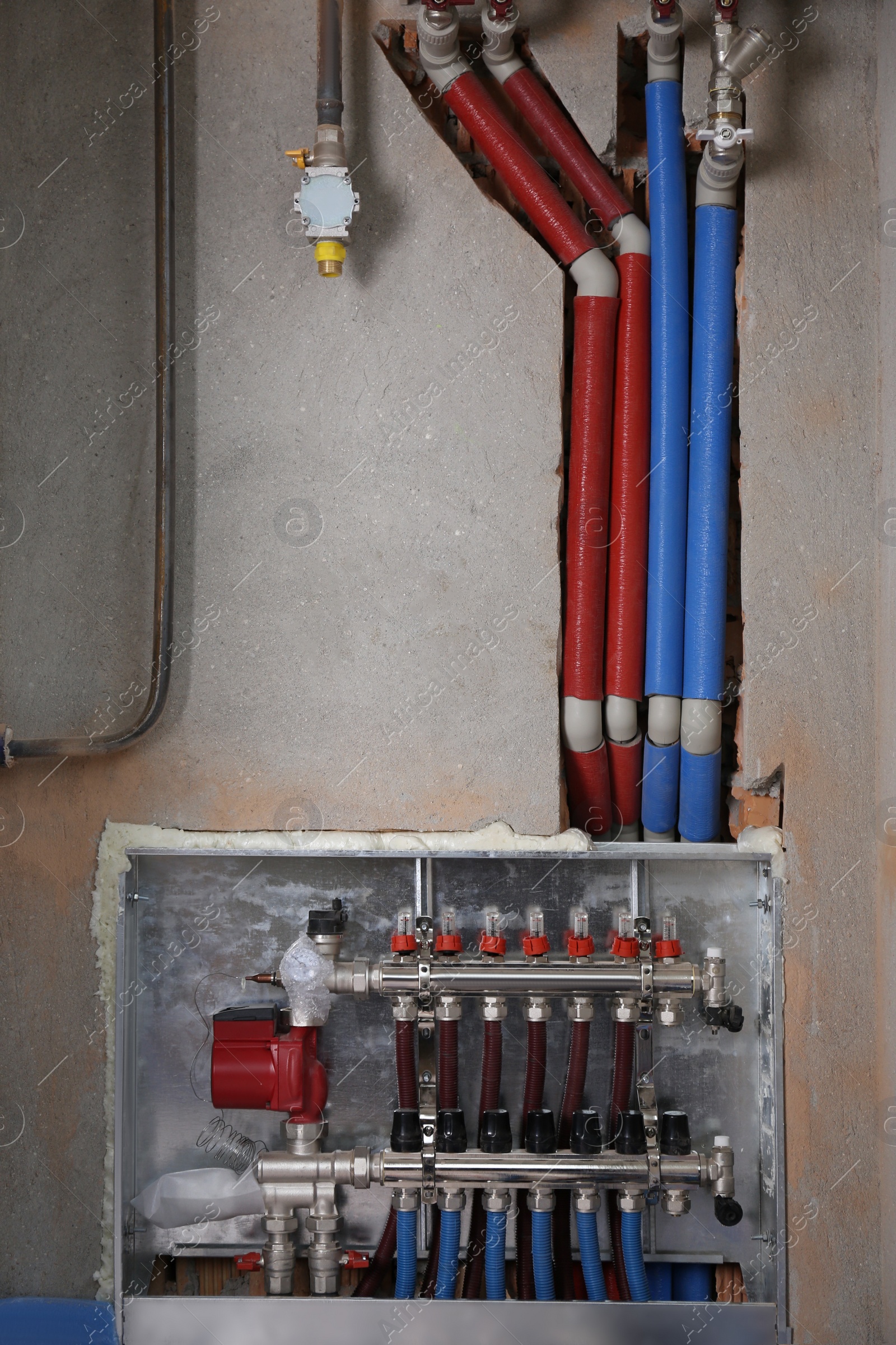 Photo of Underfloor heating system. Manifold with pipes in building