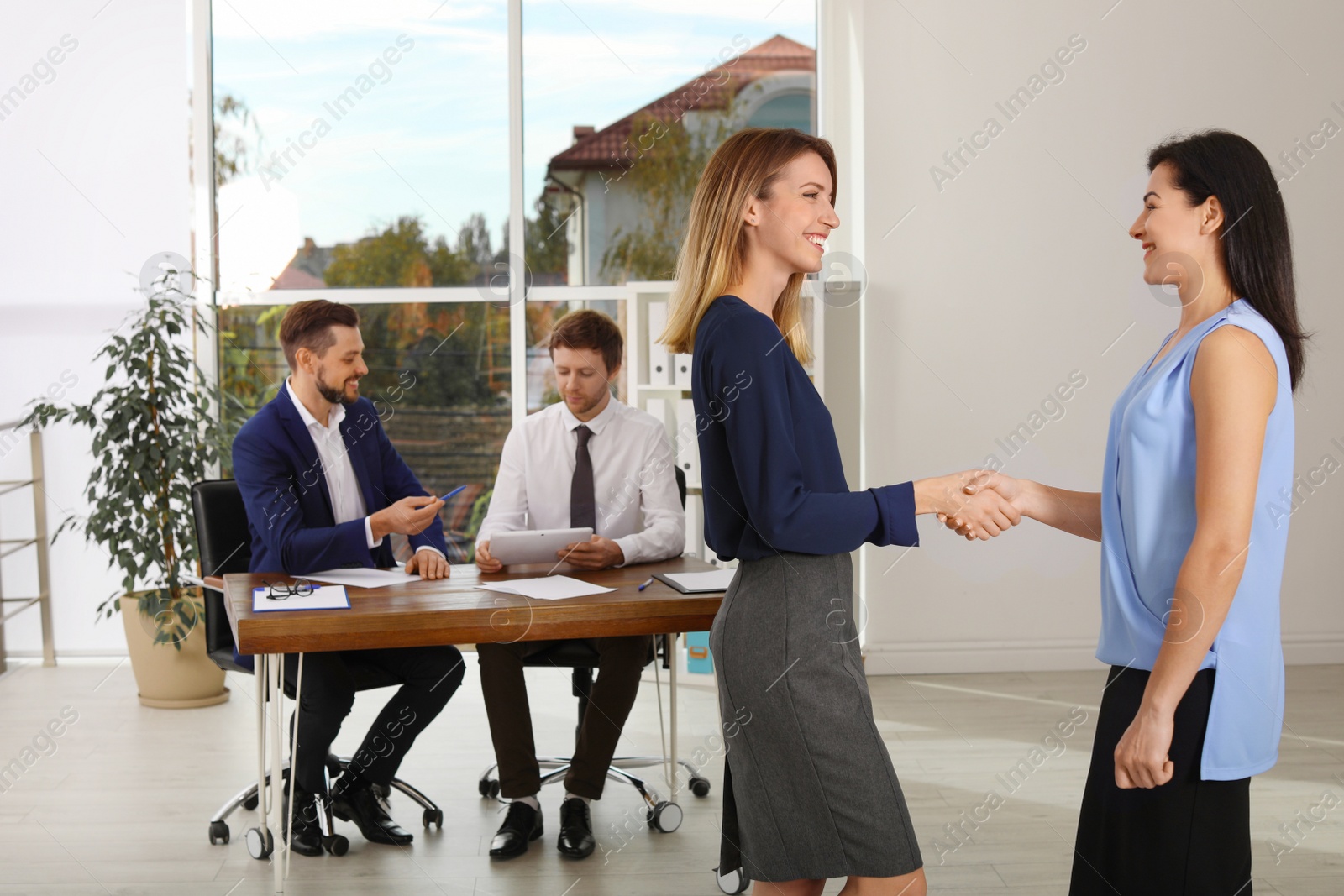 Photo of Human resources manager shaking hands with applicant during job interview in office