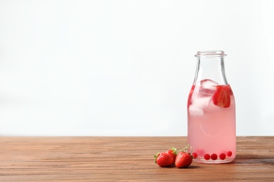 Photo of Natural lemonade with berries in bottle on wooden table