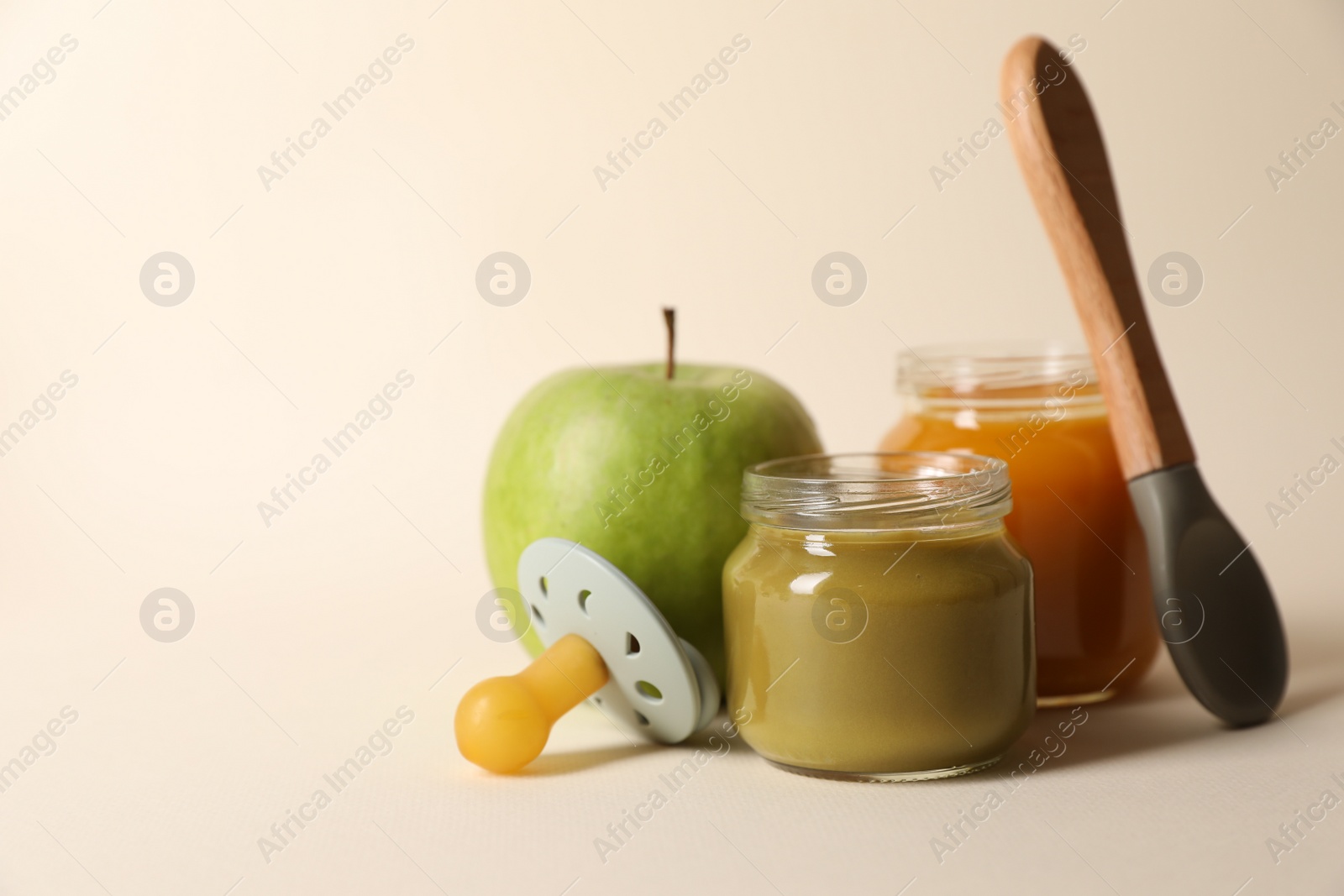 Photo of Healthy baby food, apple, pacifier and spoon on beige background. Space for text