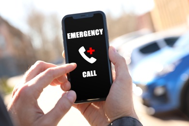 Image of Hotline service. Man making emergency call via smartphone outdoors, closeup