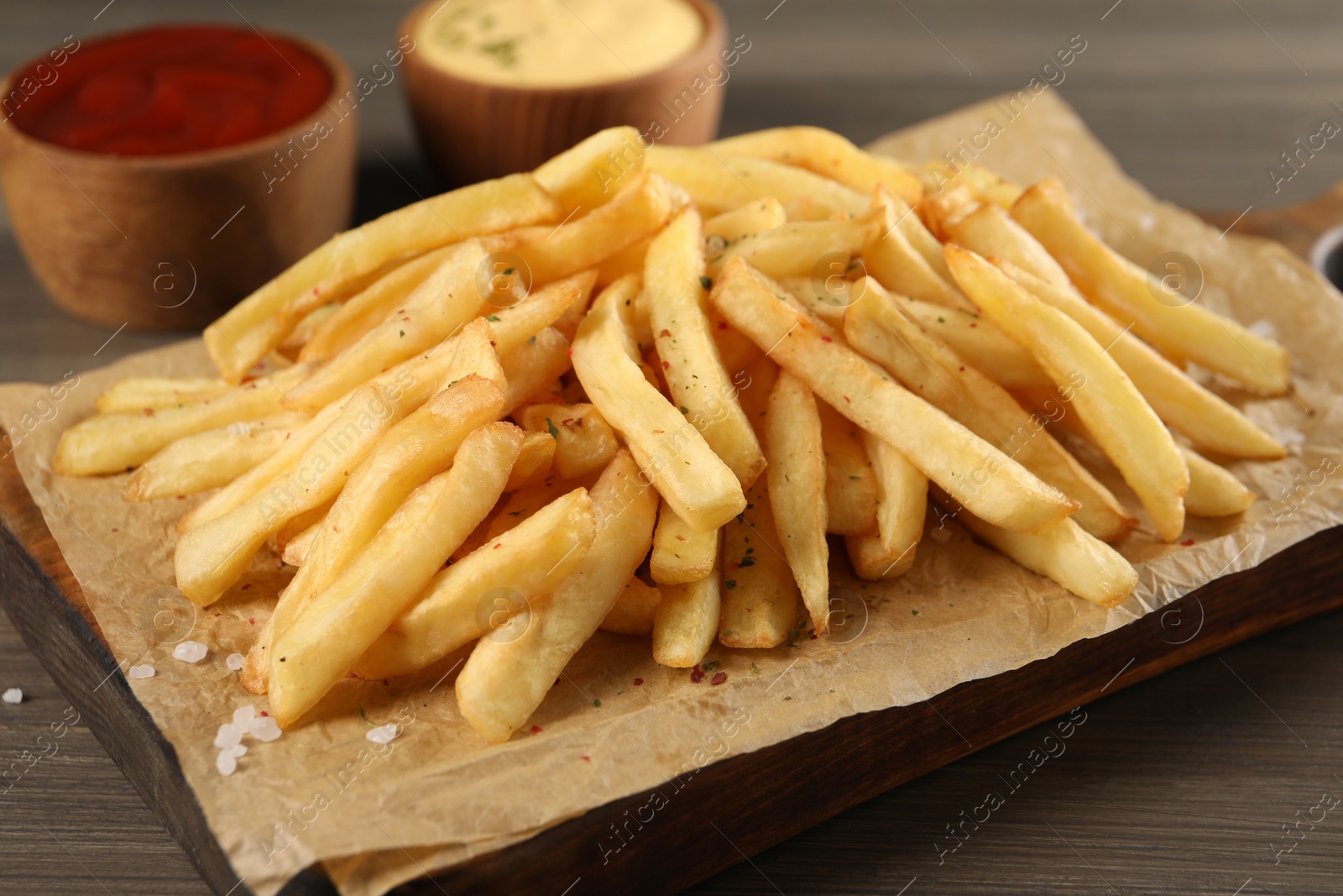 Photo of Delicious french fries on wooden table, closeup view