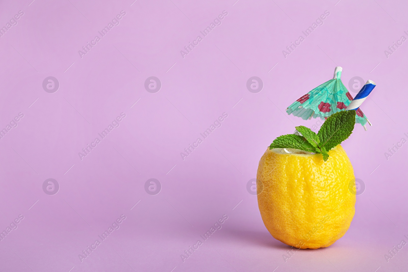 Photo of Creative image of summer cocktail made with lemon, mint, straw and umbrella on color background, space for text