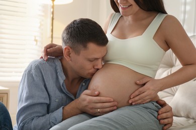 Man kissing his pregnant wife's belly at home