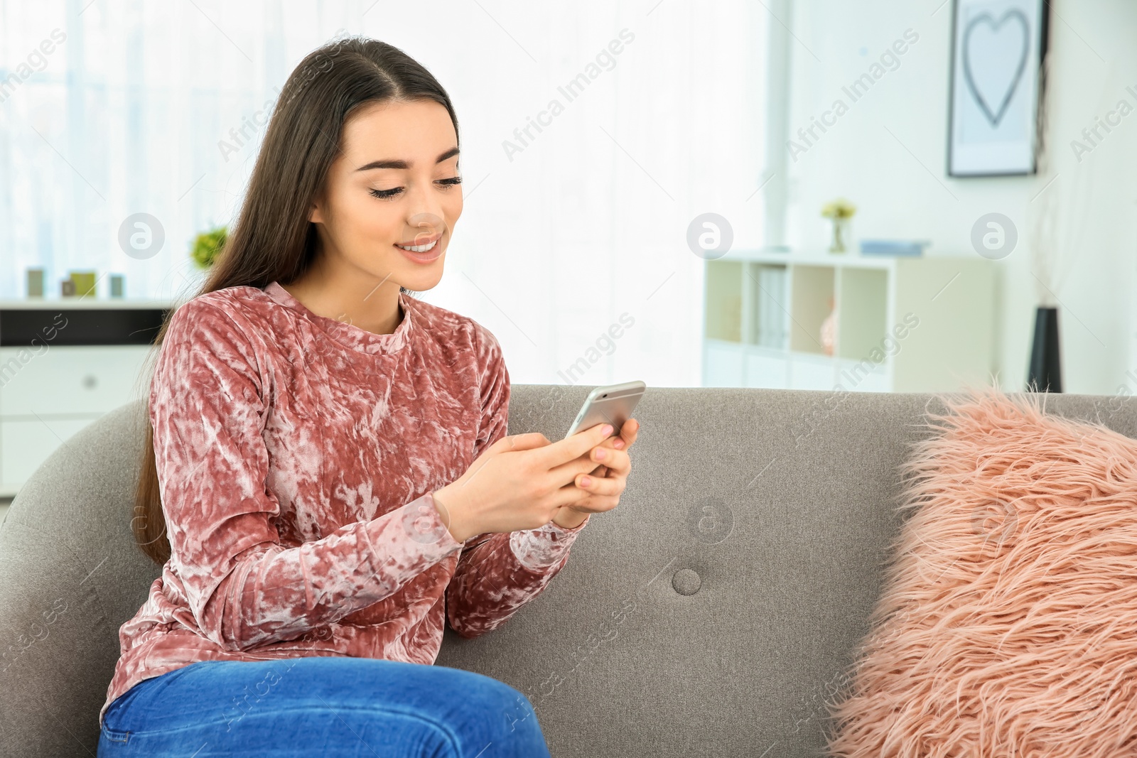 Photo of Attractive young woman using mobile phone at home