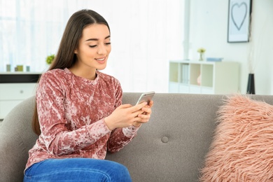 Photo of Attractive young woman using mobile phone at home