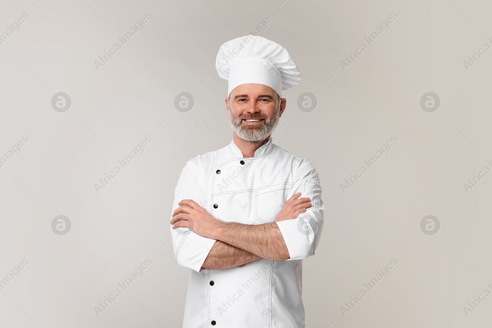 Photo of Happy chef in uniform on grey background