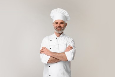 Happy chef in uniform on grey background