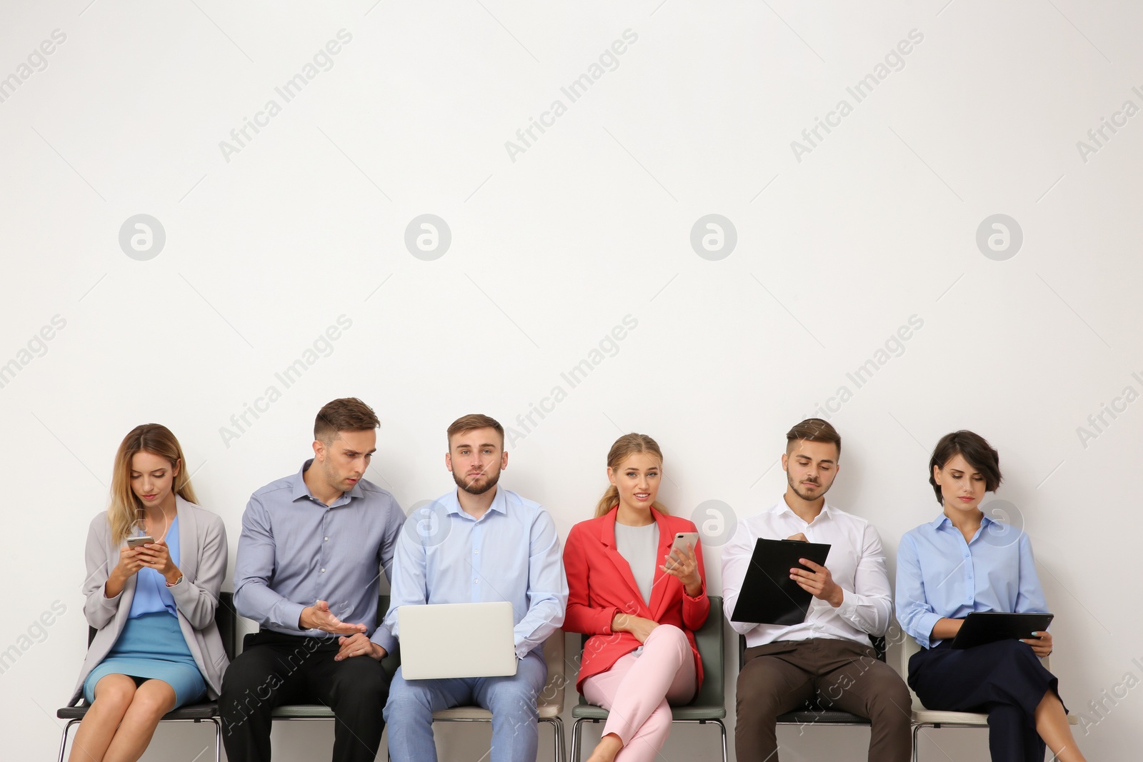 Photo of Group of young people waiting for job interview near light wall