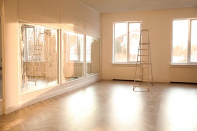 Photo of Spacious empty room with new parquet flooring and mirrors