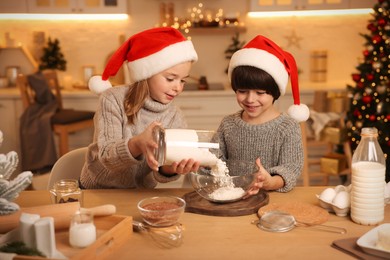 Photo of Cute little children making dough for Christmas cookies in kitchen