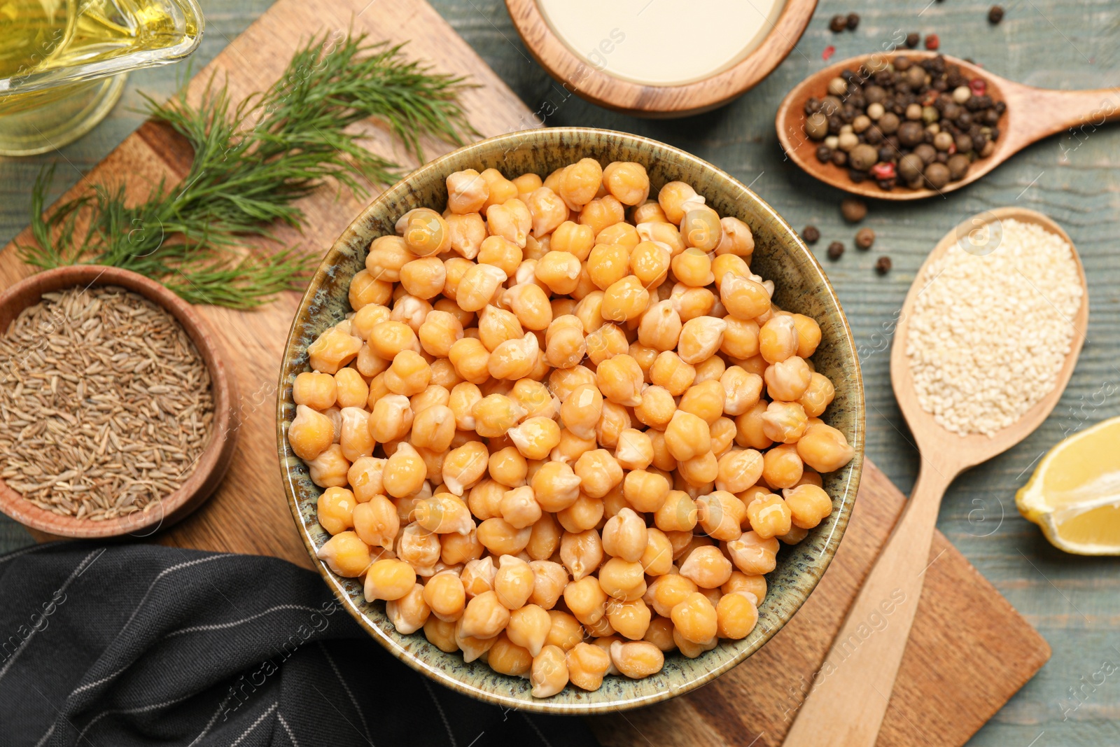 Photo of Delicious hummus and different ingredients on light blue wooden table, flat lay