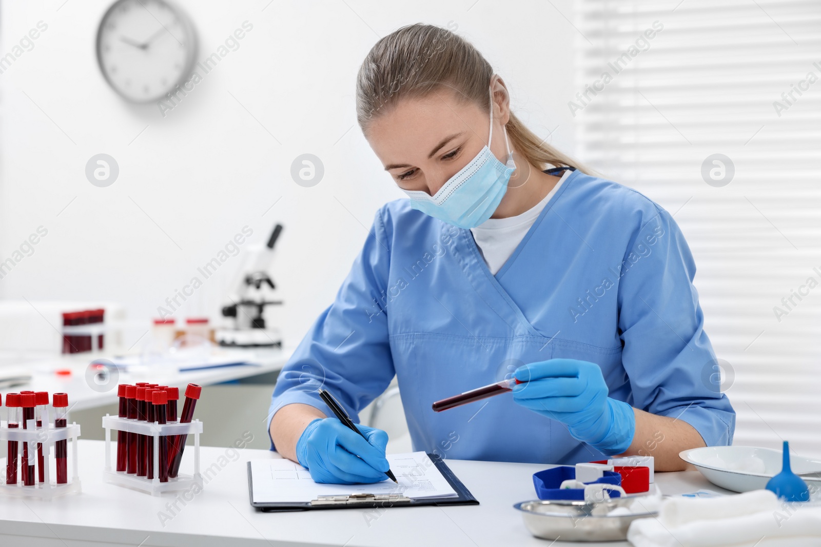 Photo of Laboratory testing. Doctor with blood samples in tubes at white table indoors