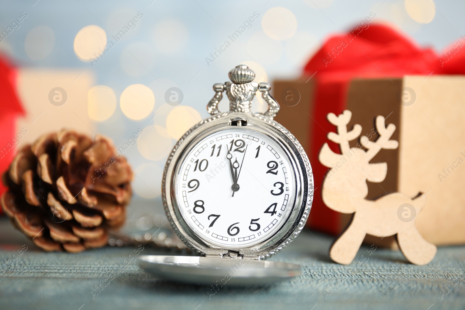 Photo of Pocket watch and festive decor on table against blurred lights. New Year countdown