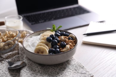 Delicious granola in bowl on white wooden table, closeup