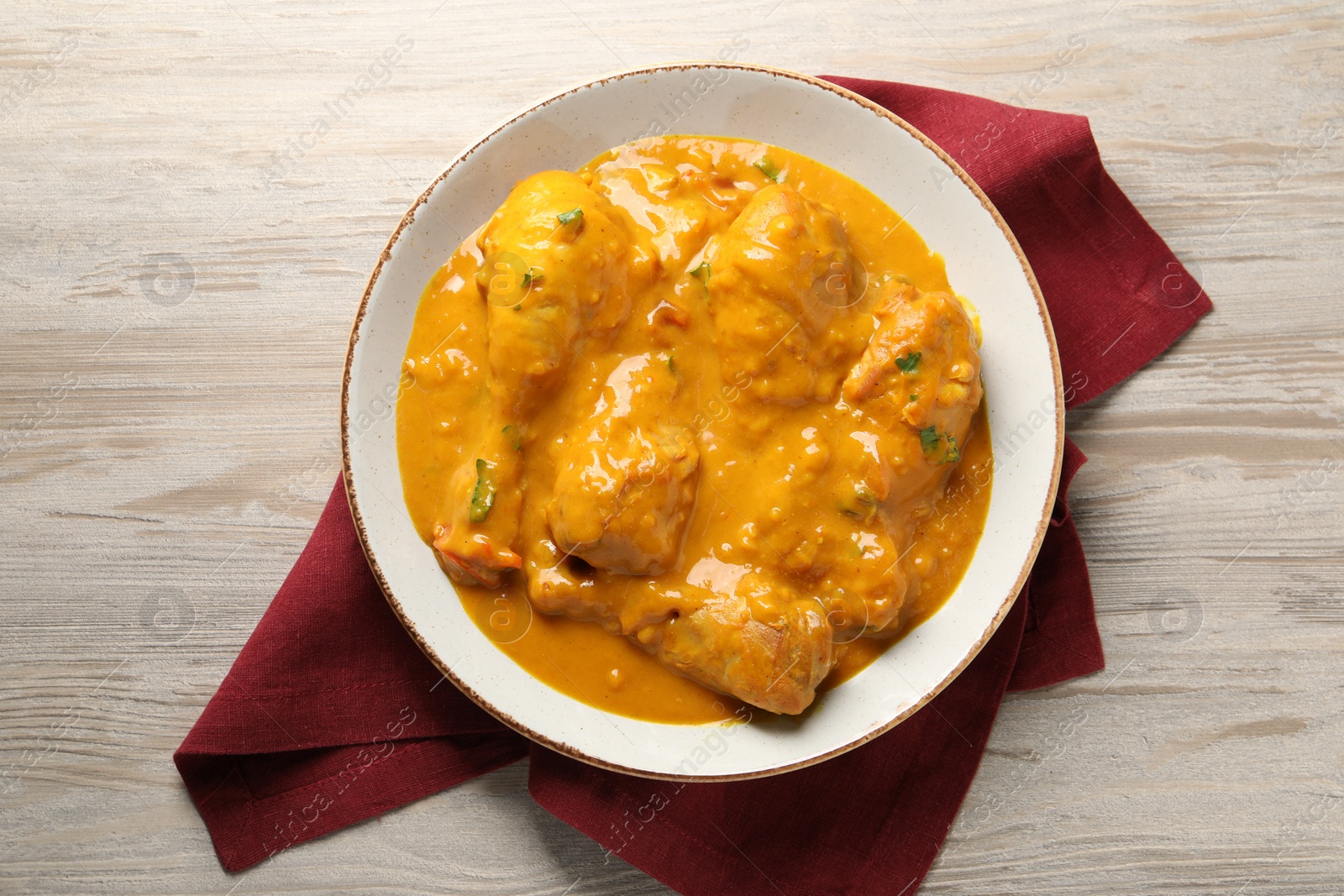 Photo of Tasty chicken curry on wooden table, top view