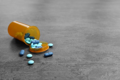 Photo of Container with different pills on grey background