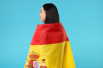 Woman with flag of Spain on light blue background