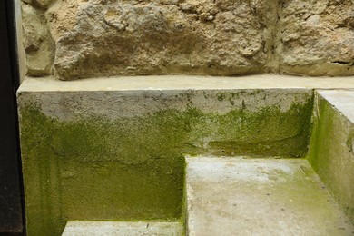 Stone wall with green moss near stairs outdoors