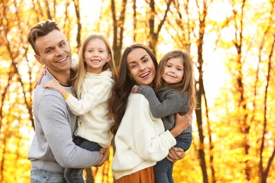 Photo of Happy family with little daughters in park. Autumn walk