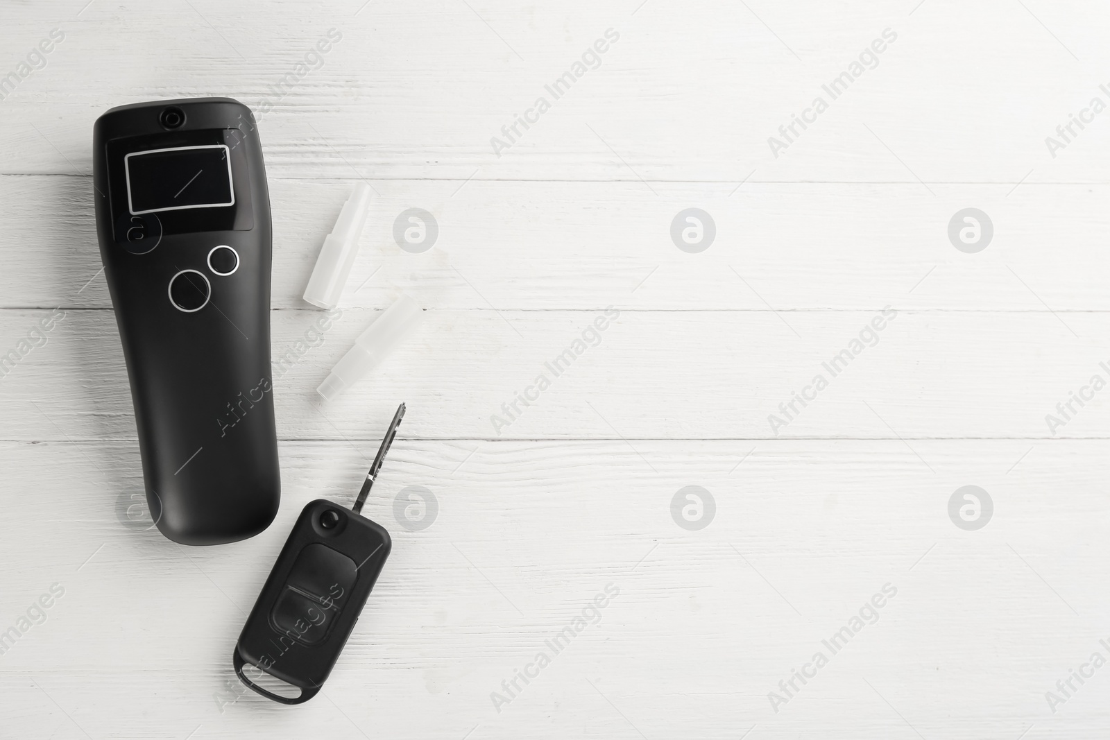 Photo of Modern breathalyzer, mouthpieces and car key on white wooden background, flat lay. Space for text