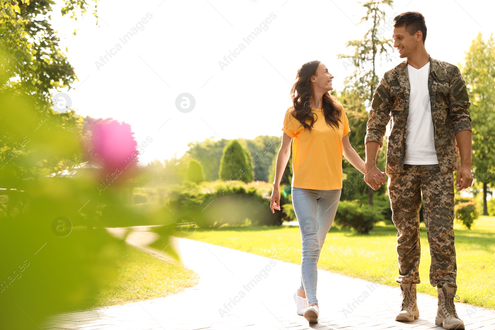 Photo of Man in military uniform walking with his girlfriend at sunny park