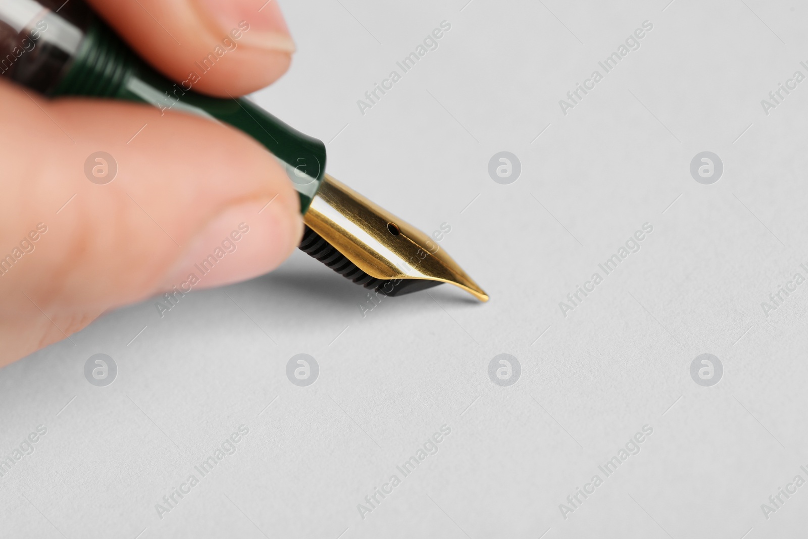 Photo of Woman with fountain pen above white paper, closeup. Space for text