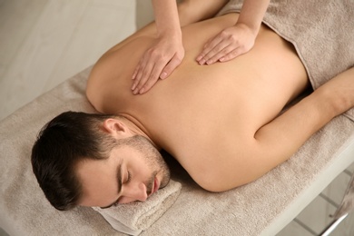 Photo of Handsome man receiving back massage in spa salon