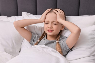 Photo of Little girl suffering from headache in bed