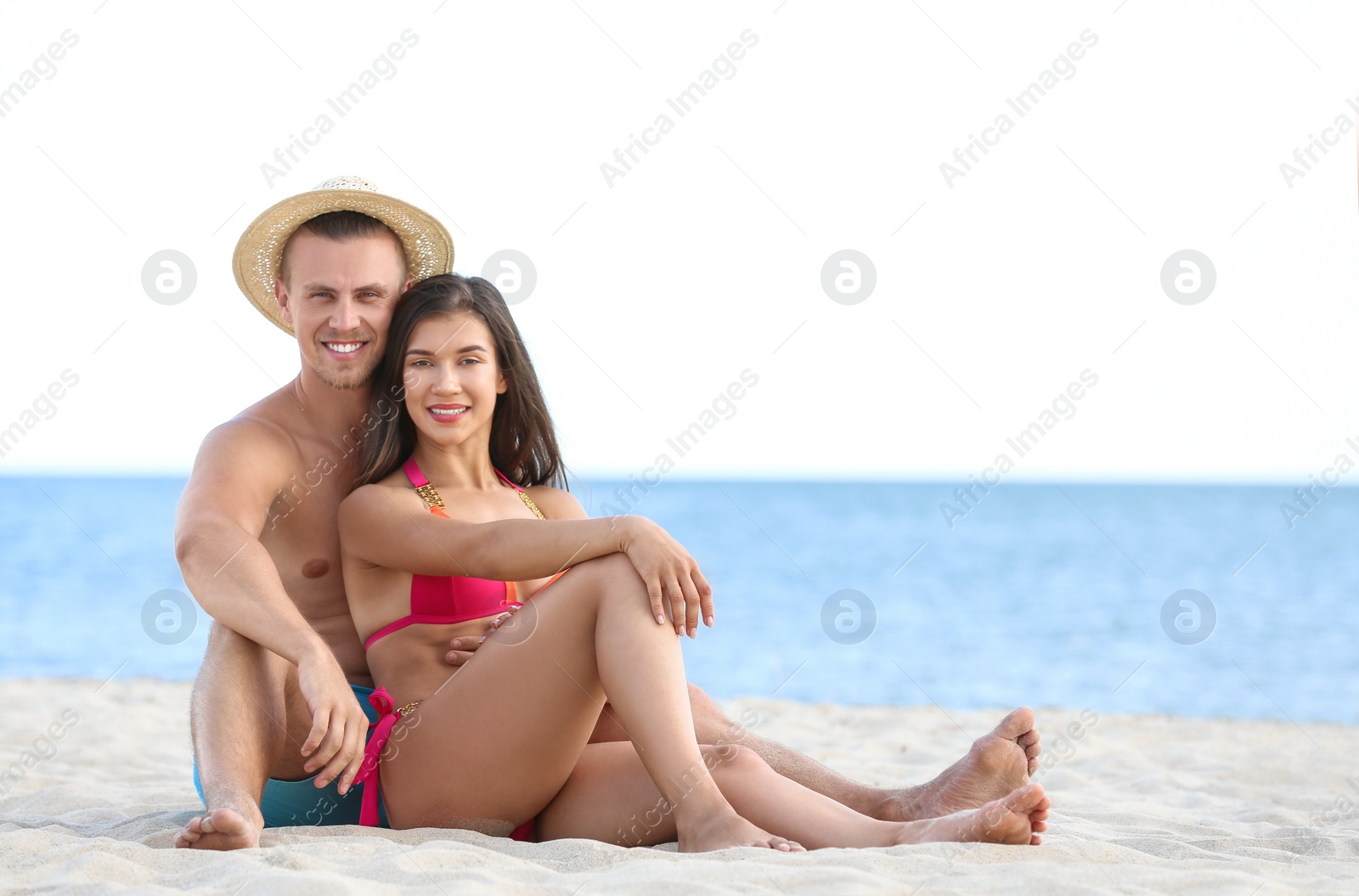 Photo of Young woman in bikini spending time with her boyfriend on beach. Lovely couple