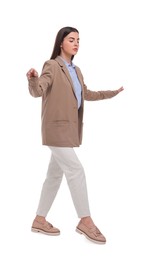 Beautiful young businesswoman walking on white background